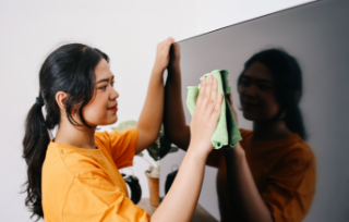 young-asian-woman-cleaning-tv-screen-with-rag